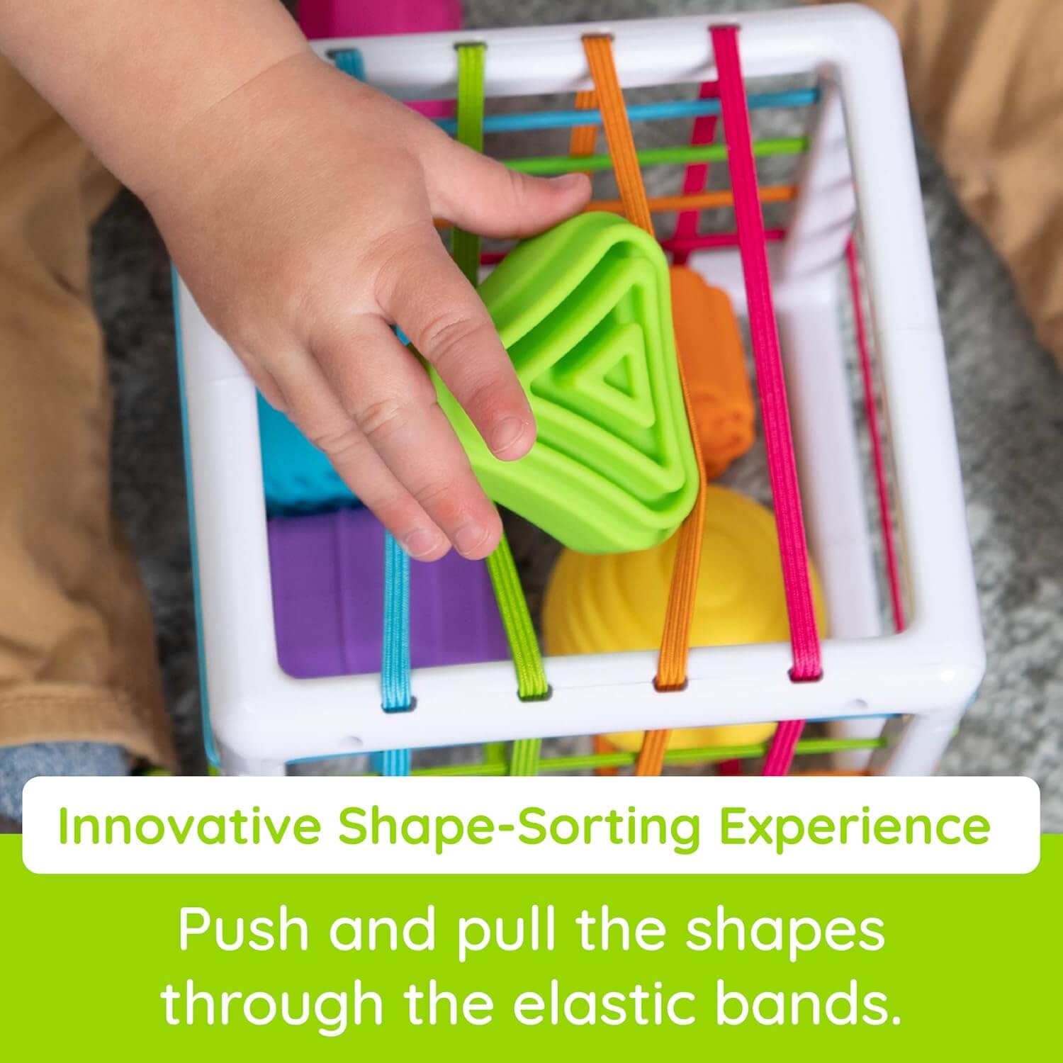 Fat Brain Toys InnyBin – sensory shape‑exploration cube with six chunky, textured blocks (cube, diamond, sphere, triangle, flower, logo) and elastic bands for frustration‑free fine motor play