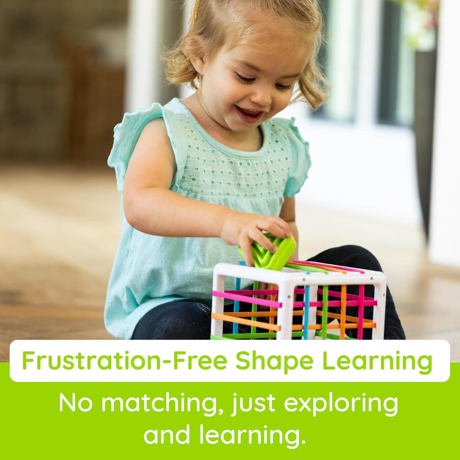 Fat Brain Toys InnyBin – sensory shape‑exploration cube with six chunky, textured blocks (cube, diamond, sphere, triangle, flower, logo) and elastic bands for frustration‑free fine motor play