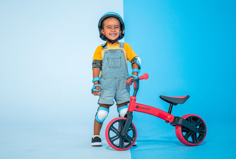 Velo Junior red balance bike for toddlers – two‑stage no‑pedal training bike with dual rear wheels, adjustable seat and handlebars, lightweight aluminum frame and puncture‑proof wheels