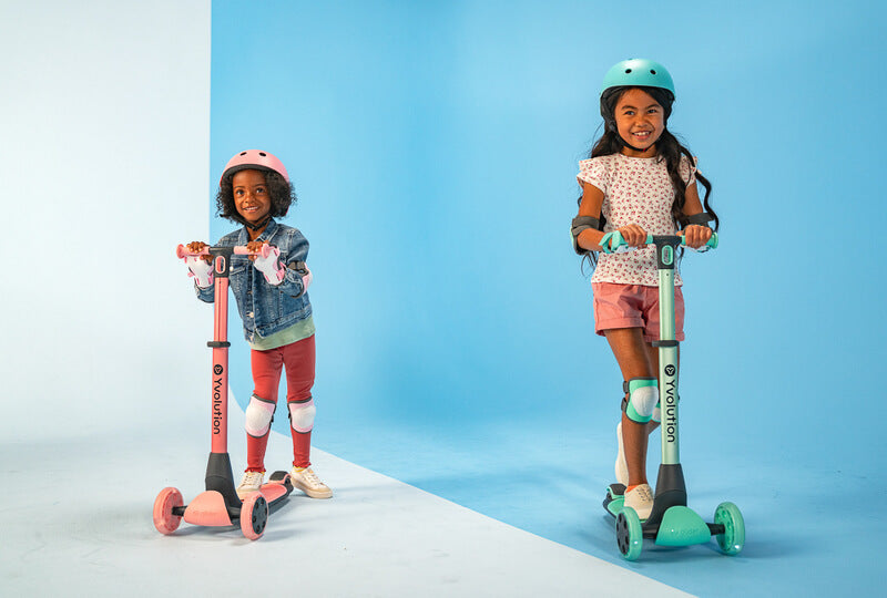 YGlider Nua green 2‑in‑1 foldable lean‑to‑steer scooter – lightweight kids’ scooter with adjustable arc‑folding handlebar, LED front wheels, wide rear wheel and wall‑mount accessory