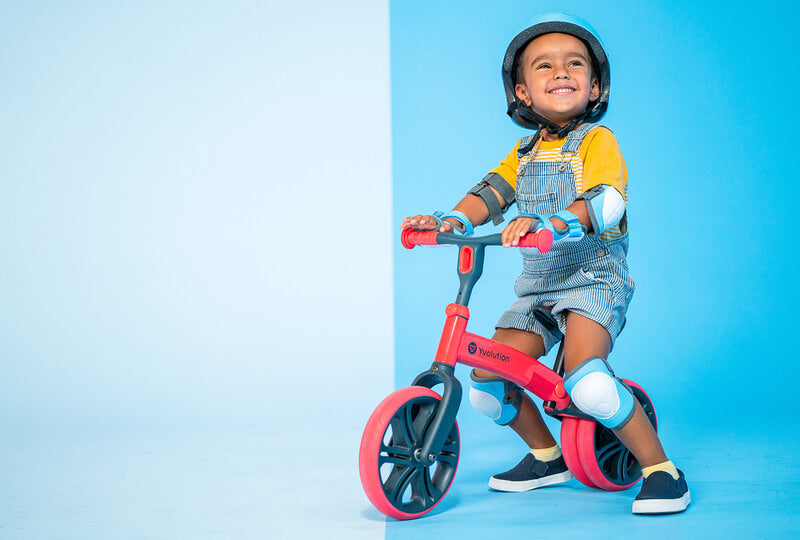 Velo Junior red balance bike for toddlers – two‑stage no‑pedal training bike with dual rear wheels, adjustable seat and handlebars, lightweight aluminum frame and puncture‑proof wheels